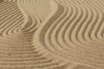 Fototapeta na wymiar Zen garden, abstract drawing of waves on the sand, the concept of harmony, balance and meditation, spa, massage, relaxation, sand texture background, wallpaper, shallow depth of field,