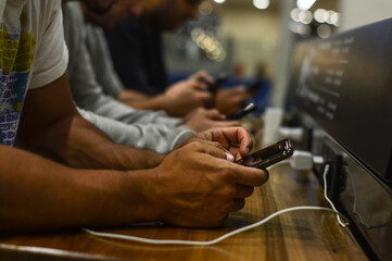 manos de hombres con teléfonos celulares conectados trabajando, en redes sociales o de ocio - obrazy, fototapety, plakaty