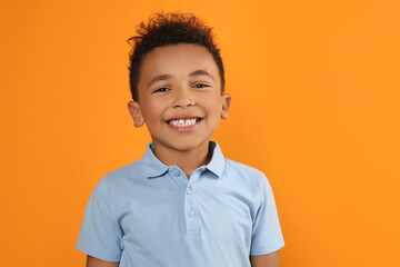 Portrait of cute African-American boy on orange background