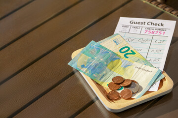 Wooden plate with payment for order and receipt on table, space for text. Leave tip