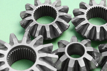Different stainless steel gears on light green background, closeup