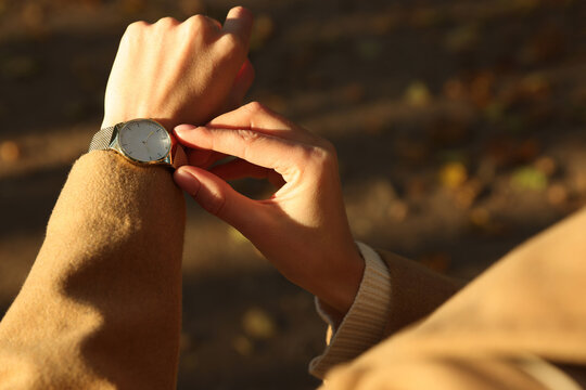 Woman checking time on watch outdoors, closeup. Being late concept