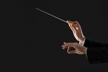 Professional conductor with baton on black background, closeup. Space for text - obrazy, fototapety, plakaty
