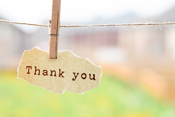 Thank you phrase printed torn paper hanging on a string with clothespin