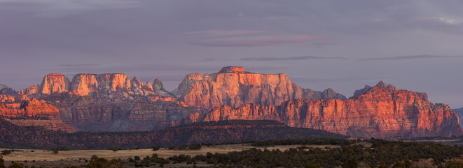 West Temple, Mt. Kinesava and the surrounding mountains of Zion National park Utah, USA, glow red and orange in the light of the setting sun, as seen from Smith Mesa on a chilly winter evening.