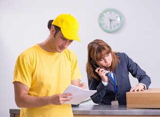 Young male courier delivering box to hotel's reception