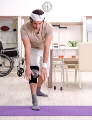 Fototapeta premium Injured young man doing exercises at home