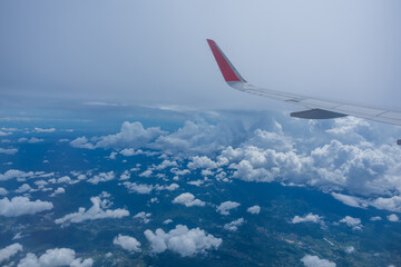 Naklejka na ściany i meble Airplane wing flying above the sky with white clouds. View from aircraft window. flying and traveling concept.