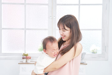 家で泣く赤ちゃんをあやす母親
