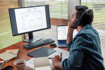 Focused man interior designer in headphones works in home office. High quality photo