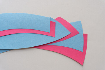 overlapping construction paper shapes in blue and pink or red on beige paper