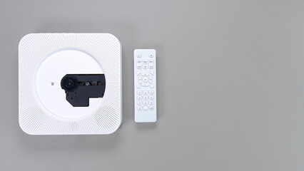 Stylish white portable compact CD player with controller on grey background. Retro vintage trending...