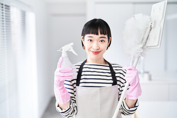 掃除道具を持つ若い女性