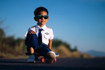 A boy in a white pilot suit sits on a skateboard at one of the streets