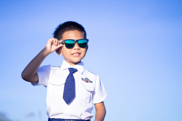 A boy wearing dark glasses in a pilot suit on a blue tone background