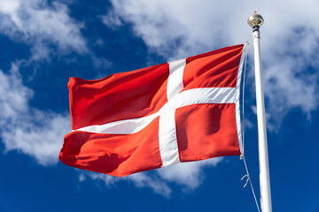 Naklejka na ściany i meble Danish flag isolated on the blue sky with clouds. Close up waving flag of Denmark.