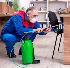 Old professional contractor doing pest control in the office