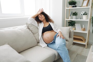 Pregnant woman headache lies at home on the couch fatigue and heaviness in the last month of pregnancy before childbirth, motherhood difficulties