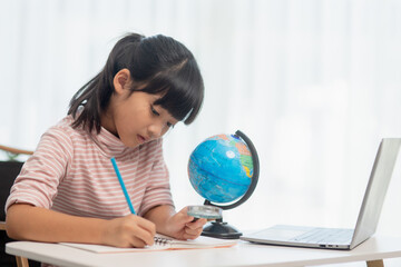 Asian little girl is learning the globe model, concept of save the world and learn through play activity for kid education at home.