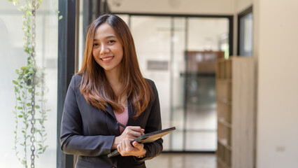 Businesswoman with a smiling face holding tablet on white background, a young Asian girl