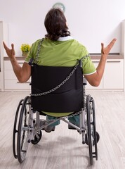 Young male invalid in wheel-chair suffering at home