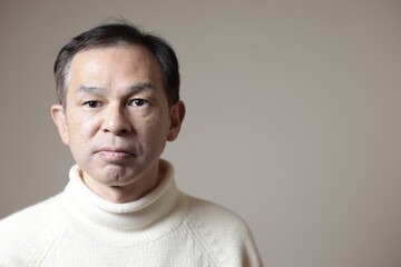 Obraz premium Middle-aged Asian man in white turtleneck wool sweater under gray background. Concept image of Warm Biz, stability in daily life, and sustainable living.