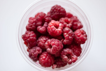 glass full of ripe raspberries on white background top view photo