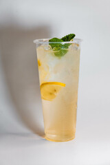 Lemonade with ice, mint and lemon slices in a transparent glass on a white background.