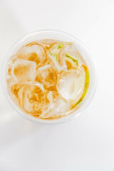 Classic lemonade with ice and lime slices in a transparent glass on a white background. View from above