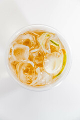 Classic lemonade with ice and lime slices in a transparent glass on a white background. View from above