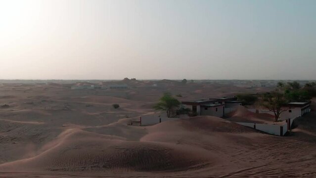 Drone flight over sand-covered Arab houses in the desert