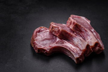 Fresh raw pork meat on the ribs with spices and herbs on a wooden cutting board