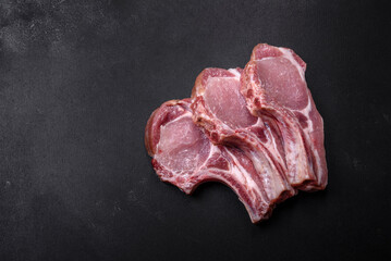 Fresh raw pork meat on the ribs with spices and herbs on a wooden cutting board