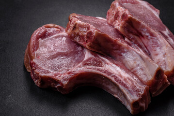 Fresh raw pork meat on the ribs with spices and herbs on a wooden cutting board