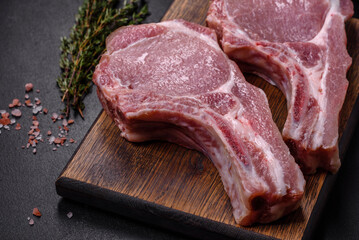 Fresh raw pork meat on the ribs with spices and herbs on a wooden cutting board