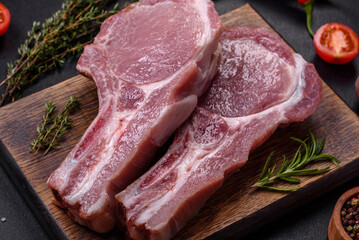 Fresh raw pork meat on the ribs with spices and herbs on a wooden cutting board