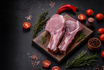 Fresh raw pork meat on the ribs with spices and herbs on a wooden cutting board