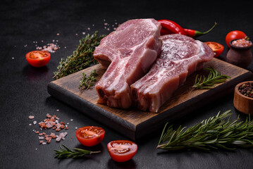 Fresh raw pork meat on the ribs with spices and herbs on a wooden cutting board