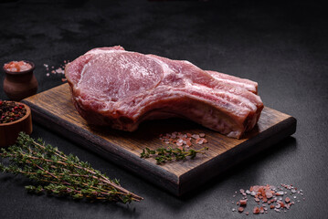 Fresh raw pork meat on the ribs with spices and herbs on a wooden cutting board