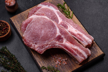 Fresh raw pork meat on the ribs with spices and herbs on a wooden cutting board