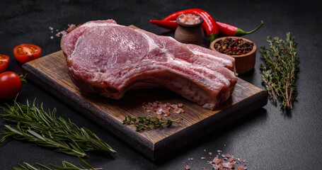 Fresh raw pork meat on the ribs with spices and herbs on a wooden cutting board