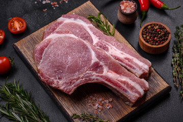 Fresh raw pork meat on the ribs with spices and herbs on a wooden cutting board