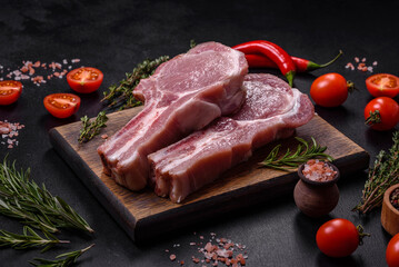 Fresh raw pork meat on the ribs with spices and herbs on a wooden cutting board