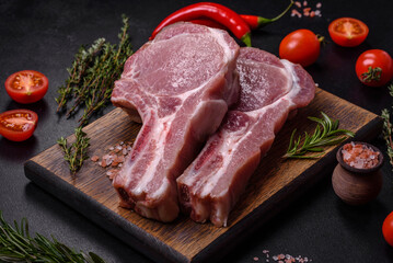 Fresh raw pork meat on the ribs with spices and herbs on a wooden cutting board