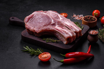 Fresh raw pork meat on the ribs with spices and herbs on a wooden cutting board