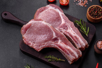 Fresh raw pork meat on the ribs with spices and herbs on a wooden cutting board