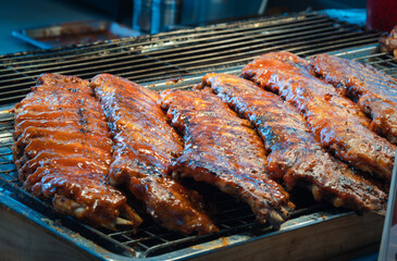 Delicious pork ribs grilled on the BBQ grill in the kitchen with smoke and flames, ready to serve.