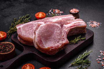 Fresh raw pork meat on the ribs with spices and herbs on a wooden cutting board