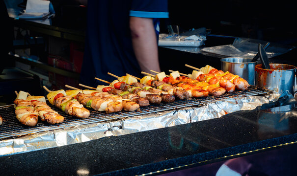 Delicious grilled meat and vegetables on a barbeque grill against smoke and flames in a busy kitchen.