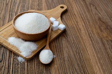 A bowl granulated sugar and sugar cubes on the board